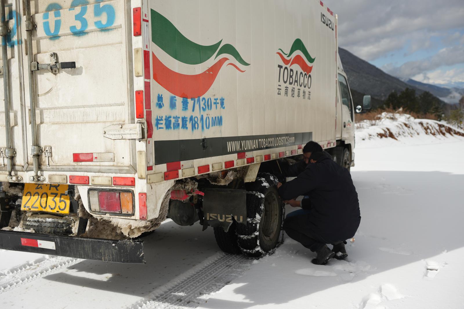 车辆驾驶员和配送员在雪地里为汽车栓防滑链